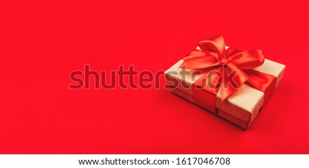 One cardboard gift box with bow on red background.