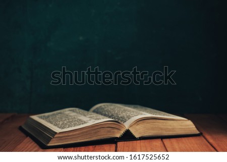 Close up Open Holy Bible on a old red wooden table. Beautiful Green wall background.	