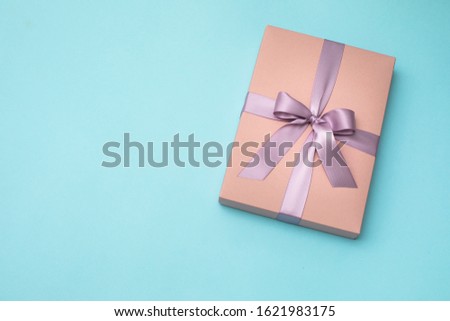 Pink gift box with ribbon and bow on blue background
