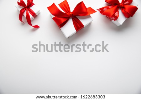 White gifts with red ribbon, present on white background top view. Happy Holidays. Valentine's day. Birthday. Women's day. Merry Christmas and Happy New Year.	
