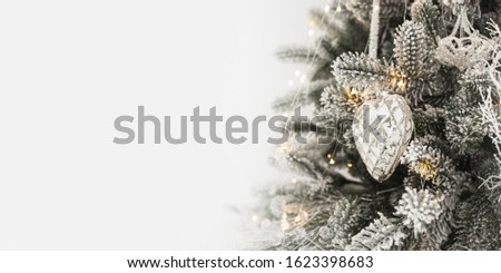 Green Christmas tree decorated with toys and bright garland on empty white color background, close up. Christmas and New Year theme wide-angle background with copyspace