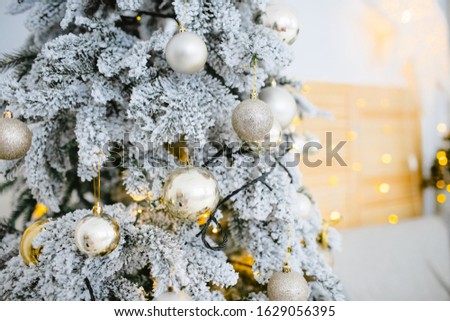 Christmas tree decorated with white and gold balls and covered artificial snow close up