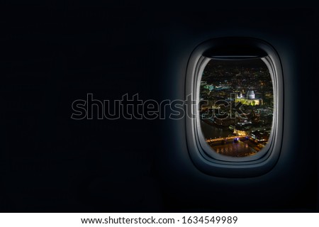 Night View from airplane porthole window of the old city of London, UK with view of river thames and St Paul’s Cathedral