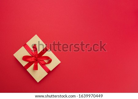 Wrapped vintage gift box with red ribbon bow on red paper background