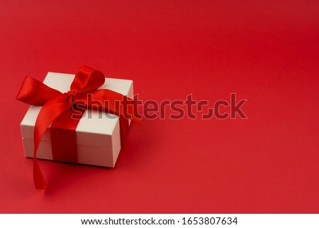 Small gift with red bow on red background. Free space for your text.
