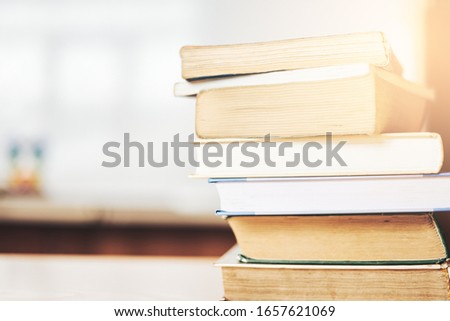 Blurred image out of focus stack of books on the table against the background of the blackboard, education concept