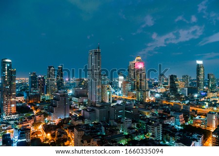 Aerial cityscape of picturesque Bangkok at night time from rooftop. Panoramic evening skyline of the biggest city in Thailand. The concept of metropolis.