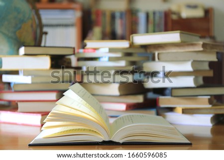 A close-up of a book opened on a library desk Stacks of books and globes in the background selective focus and shallow depth of field