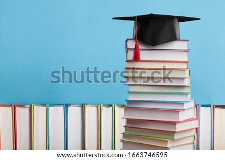 Stack of colorful school books and graduated hat