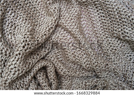 Crumpled folded beige, brown knitted fabric background, woolen knitwear plaid close up.
