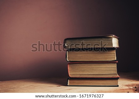 Vintage ancient books. Pattern background for design. The book on a brown wooden table table and red wall background.
