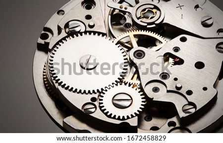 internal clock mechanism close-up view with shiny metal and gray background, photo for industry