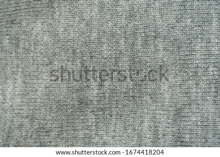 Grey knitted fabric textured background close up view.