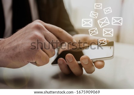The human hand holds the mobile phone with an abstract envelope icon