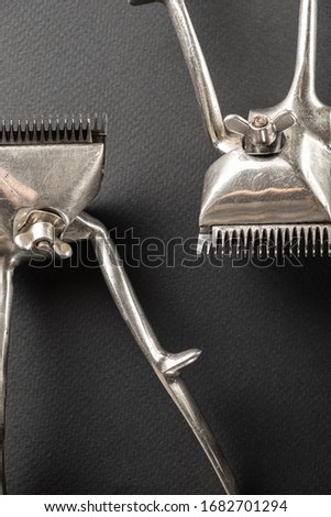 black surface are old hairdresser tools. Two vintage manual hair clippers. monochrome.