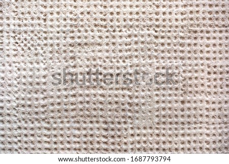 Surface of concrete wall with small round embossings as background.