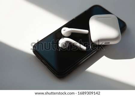 Case for white headphones storage and charging, wireless earphones, white background.