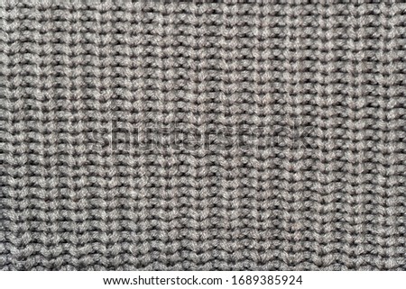 Grey knitted wool fabric background. Very warm natural knitwear handmade