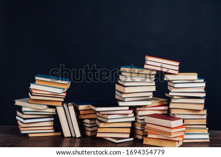many stacks of educational books for learning preparation for college exams on a black background