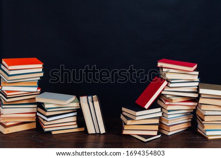 many stacks of educational books for learning preparation for college exams on a black background