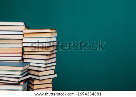many stacks of educational books for learning preparation for college exams on a green background