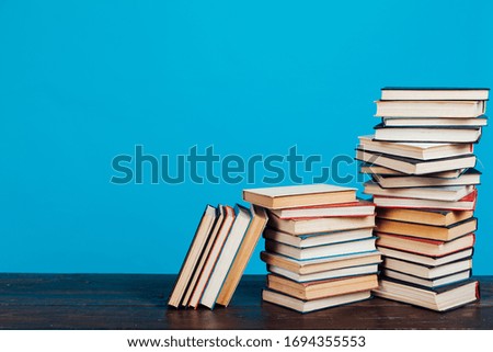 many stacks of educational books for learning preparation for college exams on a blue background