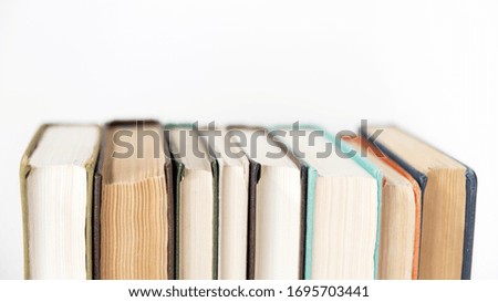 A stack of books on an isolated white background, the background of education, the concept of going back to school. A stack of colorful real books on a white background, partial view