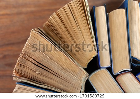 Old and well used hardback books or text books in a book shop or library. Many Books Piles. Hardback books on wooden table top view. Back to school background with copy space