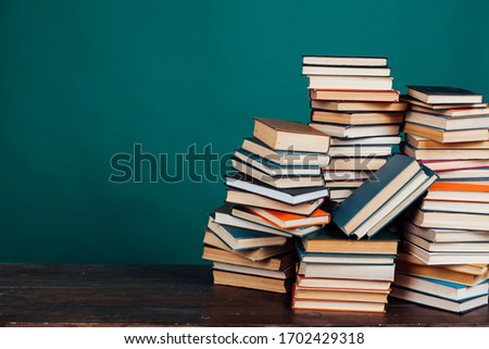 many stacks of educational books to teach in the school library on a green background