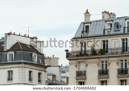 Typical old Paris architecture, facades of residential buildings with roofs, chimneys and mansards, expensive real estate concept. City residents self isolation, european lifestyle