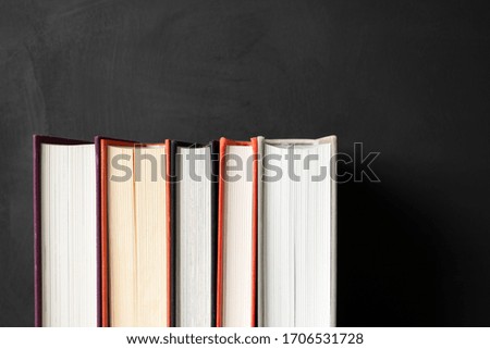 Stack of books on black chalkboard background with copy space. Home education, learning and studying. Concept back to school