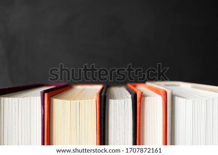Stack of books with selective focus on black background with copy space. Banner format. Home education, learning and studying