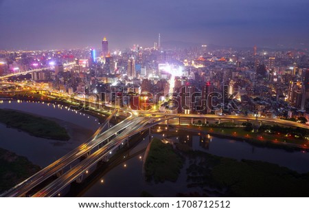 Night view of Zhongxing Bridge over Tamsui River and slip roads to the riverside Huanhe Expressway, with crowded buildings in Ximending Downtown & 101 Tower in far background in Xinyi District, Taipei