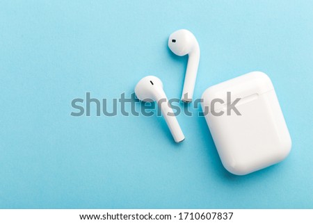 Modern wireless bluetooth headphones with charging case on a blue background. The concept of modern technology, gadgets.