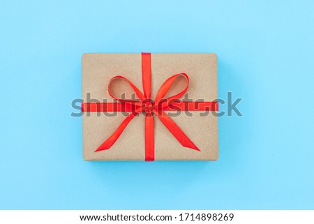 Present box package in craft paper over blue background. Top view, flat lay