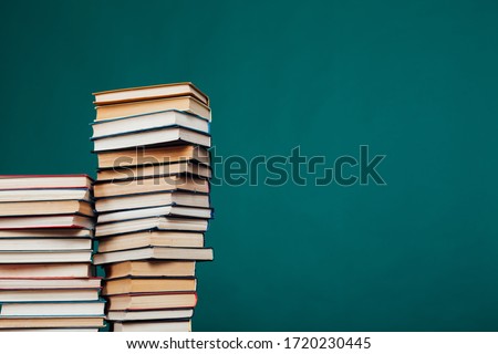 many stacks of educational books for exams at the university in the library on a green background