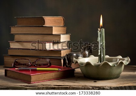 still life, Lighted candle and old books with glasses and pen on wood 
