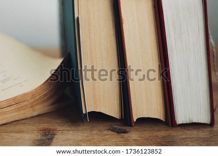 Close-up side view. Books standing on a wooden table. One book lies open.