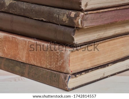 Stack of old books with shabby covers on a wooden surface. 