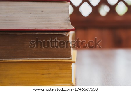 Stack of three books on a wooden table in the gazebo