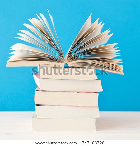 Stack of books and a open book close up on blue background. reading, education, literature, learning and back to school concept. copy space. 