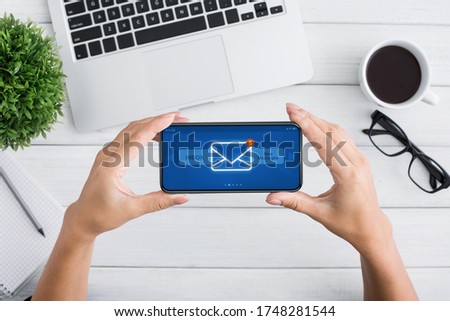 Unrecognizable Female Holding Smartphone With New Inbox Messages Notification On Screen, Sitting At Desk In Modern Office, Top View