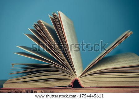 Beautiful open book on a red wooden table and blue wall background.