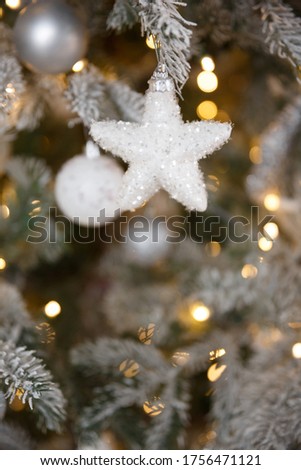 White Christmas toy hanging on a green snowy fir branch, closeup