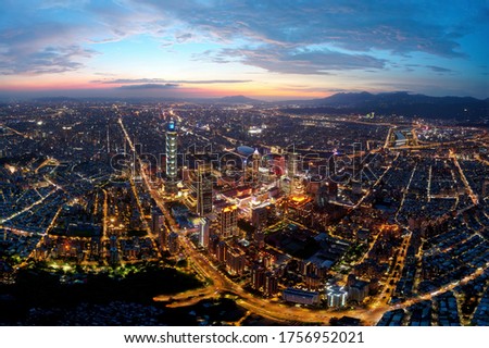 Aerial panorama of Taipei at dusk, the vibrant capital city of Taiwan, with 101 Tower standing out in Xinyi Financial District & Tamsui River winding before distant mountains under dramatic sunset sky