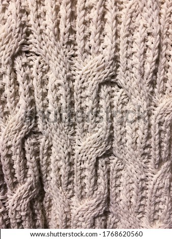 Abstract knitted background with braids.white  woolen sweater, yarn with knitting. textile. Fashion concept, top view.


