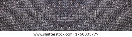 Dark grey woven fabric texture background. Knitted garment cloth pattern with many loops of wool. Woven gray cloth close up, gray color warm winter clothing or scarf design