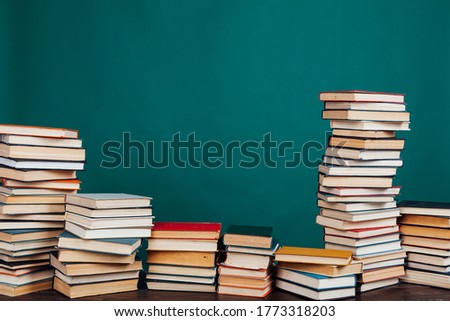 many stacks of educational books for exams in the library on the green background of the university