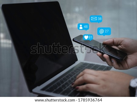 Person hand using a mobile phone and laptop with social media marketing concept.