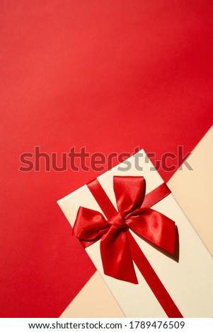 Golden present with red ribbon on the bright red background . Festive backdrop for holidays: Birthday, Valentines day, Christmas, New Year.